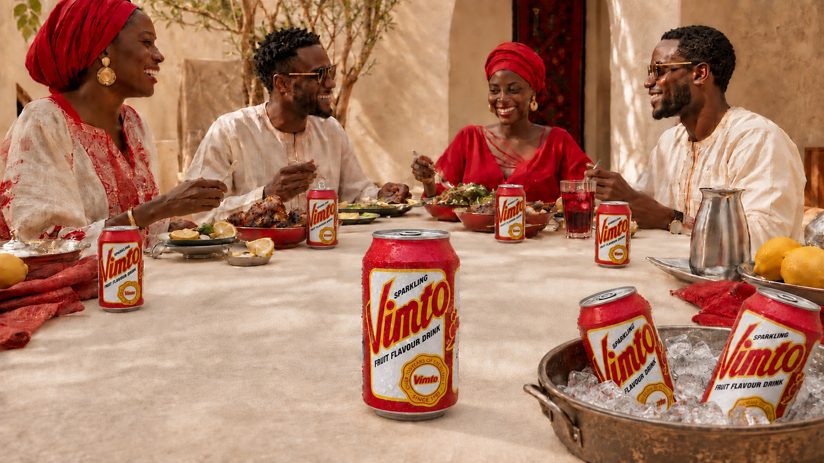 Repas partagé avec une canette Vimto Sparkling ouverte devant chaque convive, des verres servis et un bac à glaçons.